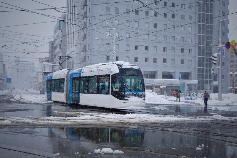 交差点を渡る、市電と冬の人の流れ