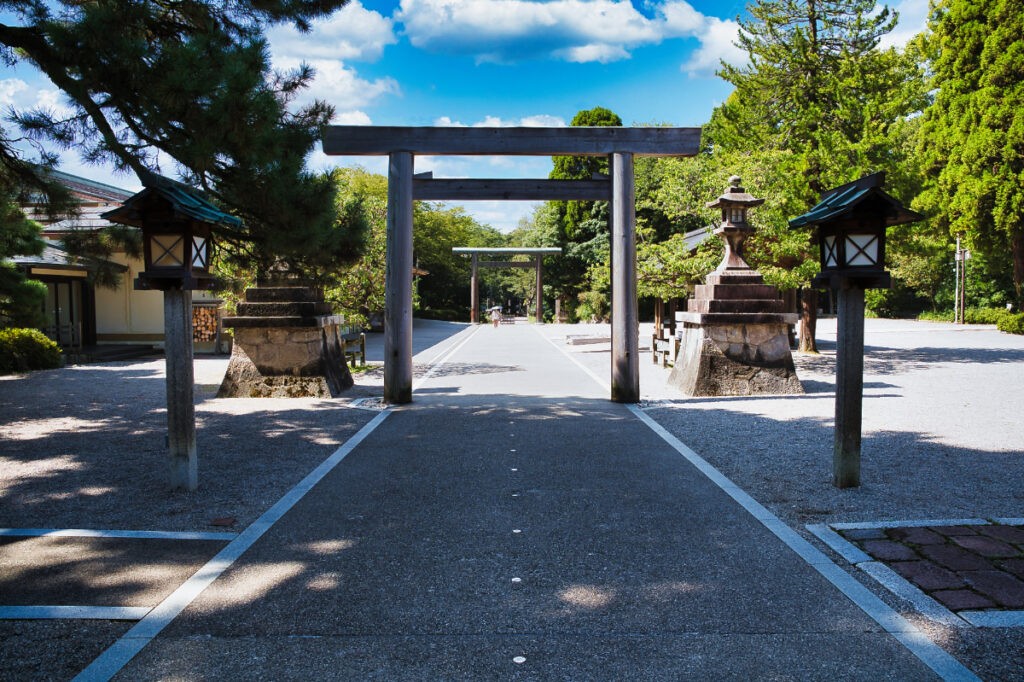 木曽檜の鳥居越しに続く参道。空の青さが、まっすぐな道をいっそう静かに見せる。
